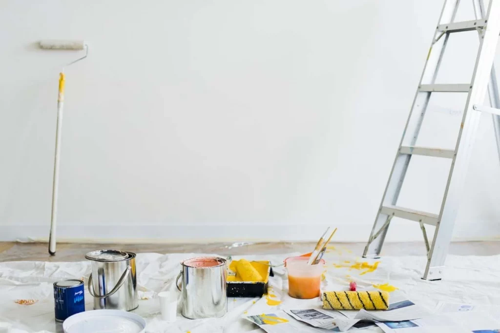 Matériel de rénovation avec pots de peinture, rouleaux et échelle dans un appartement à rénover à Montpellier