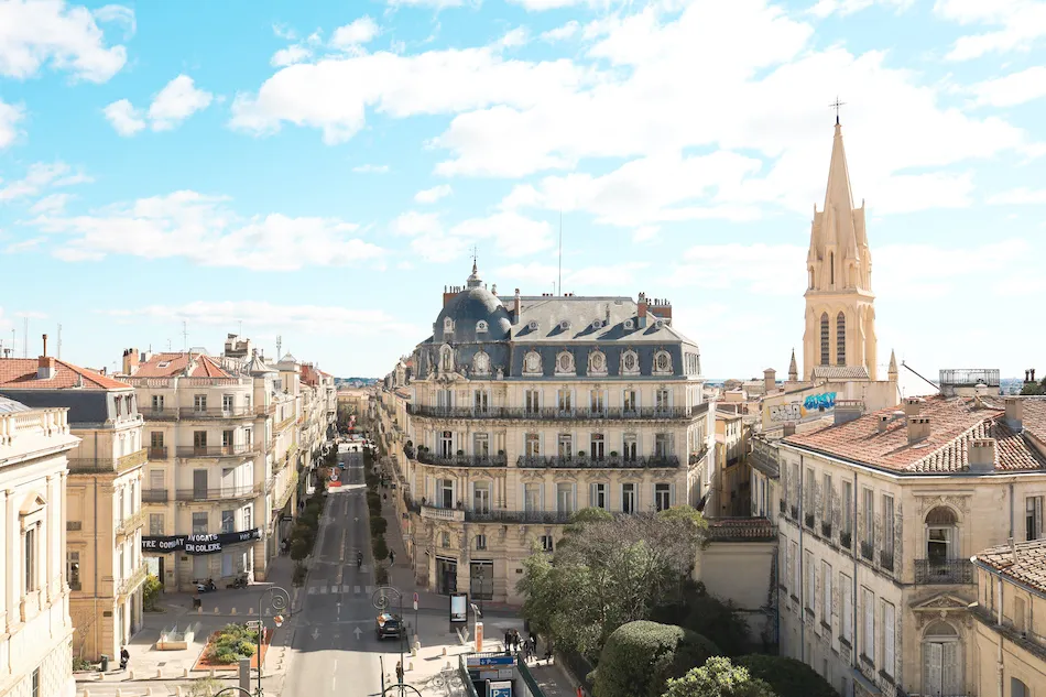 Vue du centre-ville de Montpellier avec immeubles haussmanniens et église, quartier recherché pour l’immobilier