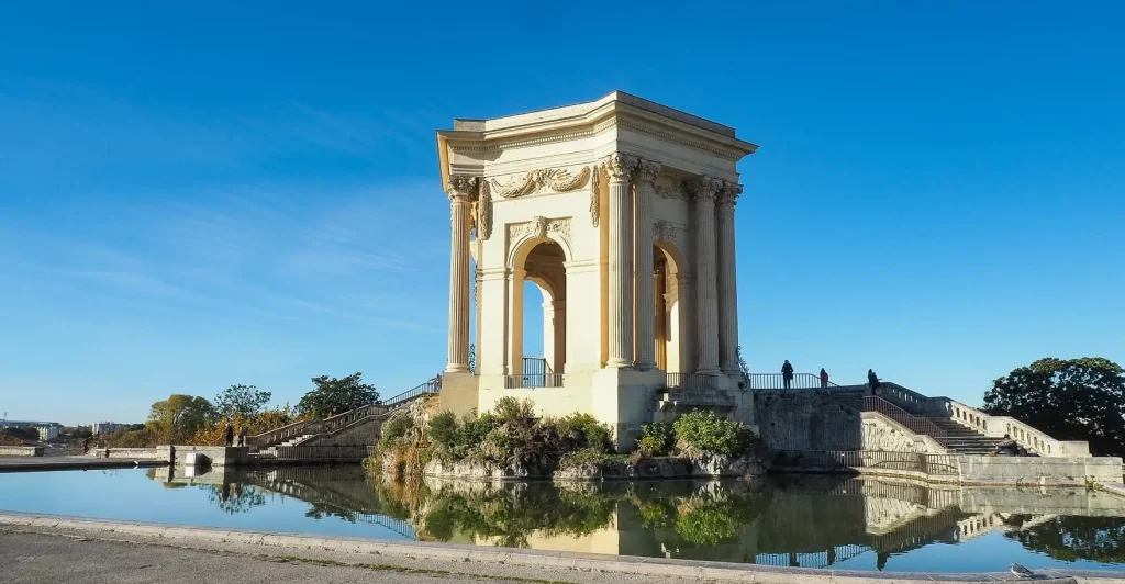 Esplanade du Peyrou à Montpellier avec le château d’eau et son bassin reflétant le ciel