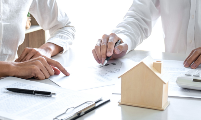 Conseiller immobilier présentant une estimation de prix de vente avec documents et maquette de maison