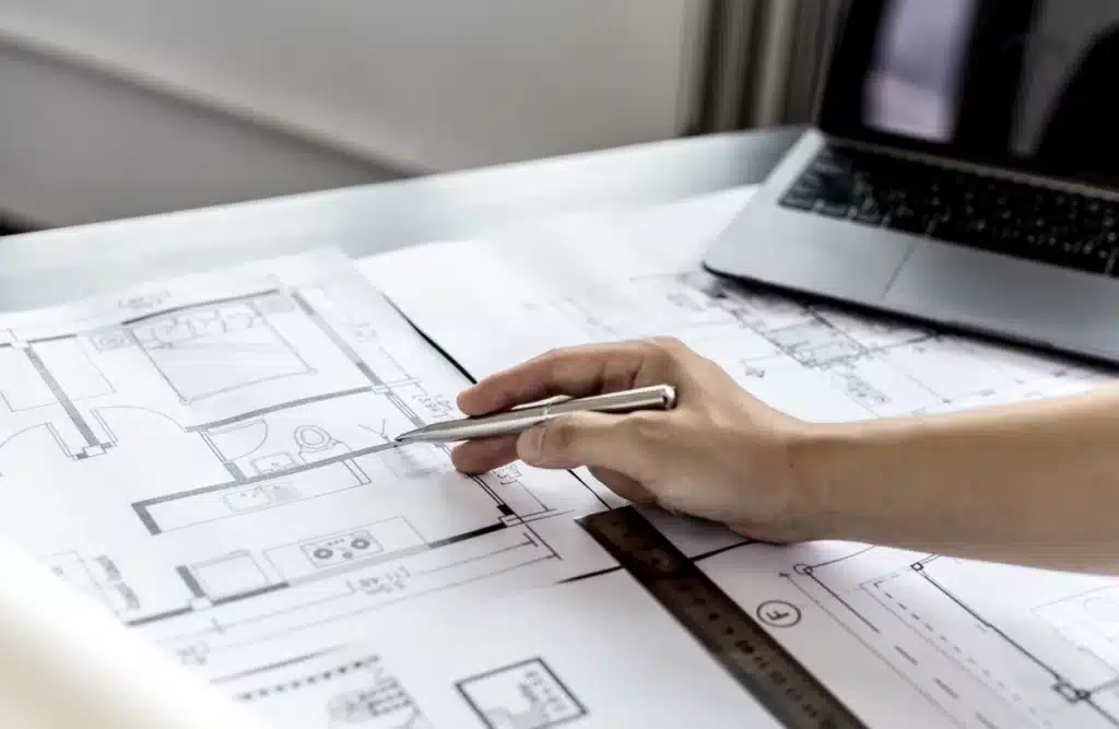 Main tenant un stylo pointant un plan d’appartement neuf à Montpellier